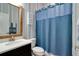 Cozy bathroom featuring blue striped wallpaper, a blue shower curtain, and a wood-framed mirror at 15521 Sandfield Loop, Winter Garden, FL 34787