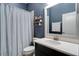 Stylish bathroom with blue striped wallpaper, a vanity, and decorative shelving for a modern touch at 15521 Sandfield Loop, Winter Garden, FL 34787
