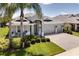Well-maintained gray house with a three-car garage, manicured lawn, and mature landscaping, including palm trees at 15521 Sandfield Loop, Winter Garden, FL 34787