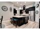 This kitchen features an island with seating, stainless steel appliances, and stylish black cabinets at 15521 Sandfield Loop, Winter Garden, FL 34787
