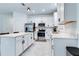 Open kitchen with white cabinets, stainless steel appliances and gray tile flooring at 2043 Rock Maple Bnd, Kissimmee, FL 34746