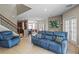 Cozy living room with an open floor plan, tile flooring, staircase, and comfortable blue furniture at 2122 Bent Grass Ave, Ocoee, FL 34761