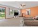Cozy living room featuring plush sofa, large window with green view, ceiling fan and colorful accent wall at 2190 Northland Rd, Mount Dora, FL 32757