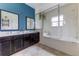 Modern bathroom with double sink vanity, framed mirrors, and luxurious soaking tub with shower at 2662 Roadster Ln, Kissimmee, FL 34746