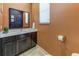 Bathroom with dark vanity, quartz countertop, large mirror, and orange accent wall at 2662 Roadster Ln, Kissimmee, FL 34746