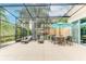 Screened-in patio with lounge chairs, outdoor dining set, and views of the tropical backyard at 2662 Roadster Ln, Kissimmee, FL 34746