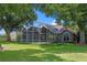 Backyard view of a home with a screened pool and patio surrounded by green grass and trees at 6631 Crenshaw Dr, Orlando, FL 32835