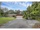 Wide view of a home with an attached garage and extended driveway under a canopy of mature trees at 7838 Sloewood Dr, Mount Dora, FL 32757