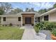 Inviting front entrance with a dark wood door, stone columns, and carefully arranged landscaping at 7838 Sloewood Dr, Mount Dora, FL 32757