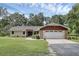 Traditional home featuring a green lawn, stone accents on the garage, and a mature tree in the front yard at 7838 Sloewood Dr, Mount Dora, FL 32757