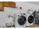 Functional laundry room featuring modern washer, dryer and utility sink with storage at 7838 Sloewood Dr, Mount Dora, FL 32757