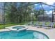 Relaxing pool and hot tub with striped lounge chairs in a screened-in enclosure, perfect for enjoying the outdoors at 9110 Stromboli Ct, Kissimmee, FL 34747