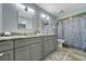 Modern bathroom featuring double vanity with granite countertops and updated fixtures, plus a shower with patterned curtain at 104 Autumn Dr, Longwood, FL 32779