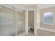 Bathroom with a separate shower stall and a soaking tub next to a window at 14425 Huntingfield Dr, Orlando, FL 32824