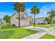 Two-story home with a two car garage, green lawn and mature palm trees at 14425 Huntingfield Dr, Orlando, FL 32824