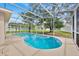 The screened-in pool has a concrete deck, trees, and fencing around the backyard at 14425 Huntingfield Dr, Orlando, FL 32824