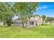 Backyard view of a screened in pool surrounded by green grass and mature trees, attached to a two story home at 14425 Huntingfield Dr, Orlando, FL 32824