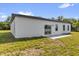 Back of the white home with a sliding glass door and two windows and a small concrete pad at 15684 Sw 37Th Cir, Ocala, FL 34473