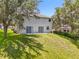 This backyard features green grass, mature trees and a gray exterior with sliding glass doors at 1602 Presidio Dr, Clermont, FL 34711