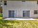 The backyard features a gray exterior with two sliding glass doors opening onto a concrete patio and grassy area at 1602 Presidio Dr, Clermont, FL 34711