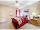 Bright bedroom featuring a ceiling fan, neutral walls and carpet, and a comfortable bed with red accents at 1602 Presidio Dr, Clermont, FL 34711
