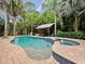 Inviting pool with a spa and covered outdoor entertaining area surrounded by lush tropical landscaping at 2342 Northumbria Dr, Sanford, FL 32771