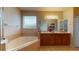 Bathroom featuring double vanity, soaking tub, large mirror, and a bright light fixture at 3552 Macauley Ct, Ocoee, FL 34761