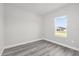 Bright, empty bedroom with wood-look flooring and a view from the window at 4662 Sw 136Th St, Ocala, FL 34473