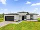 A modern home features a two car garage, gray brick paver driveway, and manicured lawn at 4662 Sw 136Th St, Ocala, FL 34473
