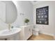 Well-lit powder room features wood floors, a round mirror, an eye-catching art piece, and modern fixtures at 5530 Settlingstone Ln, St Cloud, FL 34771
