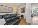 Inviting living room features stylish décor, wood floors, an area rug and a comfortable leather sofa beneath elegant artwork at 7040 Betty St, Winter Park, FL 32792