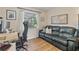 A bright office space features a comfortable leather sofa, wooden floors, and an adjustable height desk with a modern monitor at 7040 Betty St, Winter Park, FL 32792