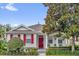 Charming single-story home featuring a red front door, decorative shutters, and a well-maintained landscaped yard at 7416 Soiree Way, Reunion, FL 34747
