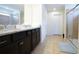 Bathroom featuring double sinks, a granite countertop, dark cabinets, and a glass enclosed shower at 1929 Nice Ct, Kissimmee, FL 34747