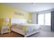 Bright bedroom featuring a double bed, yellow accent wall, white nightstands, and curtains that filter natural light at 1929 Nice Ct, Kissimmee, FL 34747