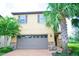 Two-story home with a grey garage door, lovely landscaping, and nice brick paver driveway at 1929 Nice Ct, Kissimmee, FL 34747