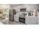 Modern kitchen featuring stainless steel appliances, light gray cabinets, and an open view to the living area at 21 Locust Ter, Ocala, FL 34472