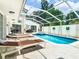 Screened-in pool area with lounge chairs, hot tub, and manicured landscaping, perfect for relaxation and entertainment at 3211 Sunrise Walk, Kissimmee, FL 34747