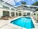 The screened-in pool area featuring a pristine pool, hot tub, lounge chairs and ample seating for entertaining at 3211 Sunrise Walk, Kissimmee, FL 34747