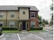 Two-story condo with manicured bushes, neutral paint, and dedicated parking spaces in front of the unit at 5953 Westgate Dr # 1821, Orlando, FL 32835