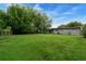 View of the expansive backyard with lush lawn and exterior of home and shed at 654 Romano Ave, Orlando, FL 32807
