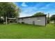 Back exterior view of home showing a large grassy lawn and covered patio at 654 Romano Ave, Orlando, FL 32807