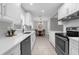 Modern kitchen with white cabinets, quartz countertops, stainless steel appliances, and open to dining area at 654 Romano Ave, Orlando, FL 32807