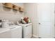 Bright laundry room with white washer and dryer, storage shelf, and modern fixtures near a white paneled door at 1023 Ladyfish Trl, St Cloud, FL 34771