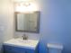 Bathroom vanity featuring blue cabinetry, brushed nickel faucet, decorative mirror, and a modern toilet at 1935 Conway Rd # M1, Orlando, FL 32812