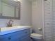 Bathroom vanity featuring blue cabinetry, brushed nickel faucet, decorative mirror, and a modern toilet at 1935 Conway Rd # M1, Orlando, FL 32812