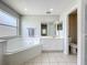 Bright bathroom featuring a soaking tub, double vanity, and white tile flooring at 238 Hunt St, Clermont, FL 34711
