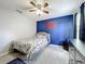 Another view of the bedroom showing the bright accent wall, ceiling fan, bed with colorful linens, and dresser at 238 Hunt St, Clermont, FL 34711