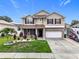 Two-story home featuring a landscaped front yard, brick accents, and attached two-car garage at 238 Hunt St, Clermont, FL 34711