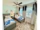Bedroom features cool tones, wood-look flooring, a ceiling fan and two twin beds at 3117 Caribbean Soul Dr, Kissimmee, FL 34747